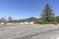 a street is empty with rocks and trees around it and mountains in the back ground