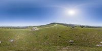 a 360 - fish eye picture of an open field and road, with stones in it