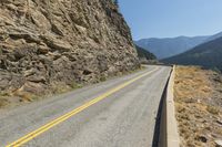 a mountain road stretches on both sides of the rocky mountainside on a clear, sunny day