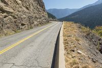 a mountain road stretches on both sides of the rocky mountainside on a clear, sunny day