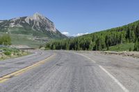 an empty road leading to some mountains in the back yard of a mountain resort with a sign that says rocky mountain