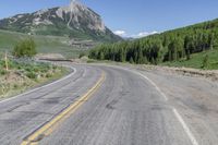 an empty road leading to some mountains in the back yard of a mountain resort with a sign that says rocky mountain