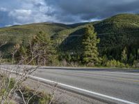 a person on a bike rides down the road with mountains in the distance along side of it