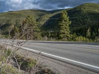 a person on a bike rides down the road with mountains in the distance along side of it