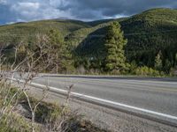 a person on a bike rides down the road with mountains in the distance along side of it