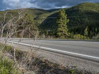 a person on a bike rides down the road with mountains in the distance along side of it