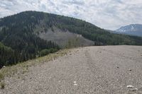 there is a road and mountains next to the highway with no cars on it and people standing at the end of it