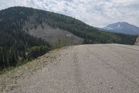 there is a road and mountains next to the highway with no cars on it and people standing at the end of it