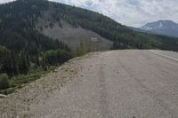 there is a road and mountains next to the highway with no cars on it and people standing at the end of it