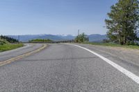 an empty road with mountains in the background and trees to the side, at high speeds