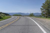 an empty road with mountains in the background and trees to the side, at high speeds