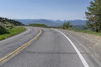 an empty road with mountains in the background and trees to the side, at high speeds