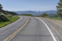 an empty road with mountains in the background and trees to the side, at high speeds