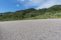 a paved road in the middle of some hills and grass with a few trees growing along the side