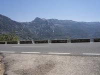 a car driving along a road in front of a mountain and sky with the mountains as far as the road