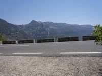 a car driving along a road in front of a mountain and sky with the mountains as far as the road