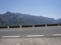 a car driving along a road in front of a mountain and sky with the mountains as far as the road