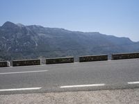 a car driving along a road in front of a mountain and sky with the mountains as far as the road