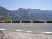 a car driving along a road in front of a mountain and sky with the mountains as far as the road