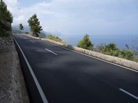a bike is riding down a road on the edge of a cliff over looking the ocean
