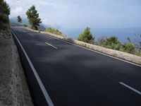 a bike is riding down a road on the edge of a cliff over looking the ocean