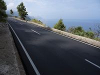 a bike is riding down a road on the edge of a cliff over looking the ocean