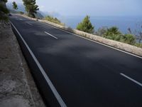 a bike is riding down a road on the edge of a cliff over looking the ocean