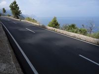 a bike is riding down a road on the edge of a cliff over looking the ocean