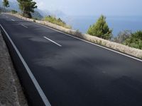 a bike is riding down a road on the edge of a cliff over looking the ocean