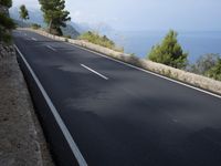 a bike is riding down a road on the edge of a cliff over looking the ocean