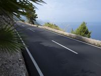a bike is riding down a road on the edge of a cliff over looking the ocean