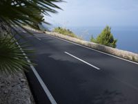 a bike is riding down a road on the edge of a cliff over looking the ocean