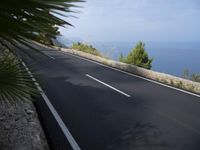 a bike is riding down a road on the edge of a cliff over looking the ocean