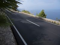 a bike is riding down a road on the edge of a cliff over looking the ocean