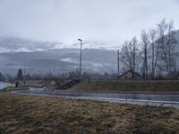 an open road with a mountain and a building in the background and some snow on the mountain