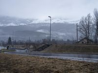 an open road with a mountain and a building in the background and some snow on the mountain