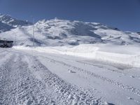 a truck drives along the snow - covered road through mountains under a clear blue sky