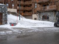 a building is full of snow and a fire hydrant outside it is almost completely surrounded by the snow