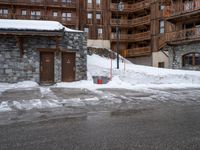 a building is full of snow and a fire hydrant outside it is almost completely surrounded by the snow