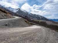 a road going up a mountain near a snow capped peak with several people on it