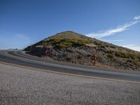 the roadway is next to an overlook looking hill with a traffic sign and post at the end