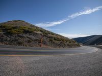 the roadway is next to an overlook looking hill with a traffic sign and post at the end