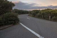 the view from a distance of a single long road with two white arrows pointing in opposite directions