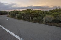 the view from a distance of a single long road with two white arrows pointing in opposite directions