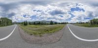 three sides of a road with mountains in the background and a sky with clouds over the top