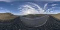 the curved road is in a view with some clouds above it and the mountain below