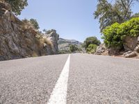 a road lined with rocks on either side of the mountains and a white line painted down between the lanes