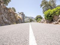 a road lined with rocks on either side of the mountains and a white line painted down between the lanes