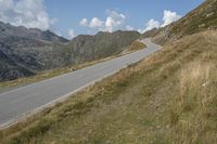 a motorcycle parked on a small mountain side road near mountains with no cars driving on it