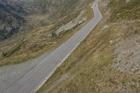 a large motorcycle is driving down the winding country road through the mountains along the grassy hillside, in front of mountains